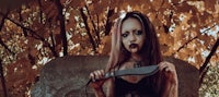 a woman holding a knife in the woods