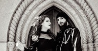 a black and white photo of a man and woman standing in front of an archway