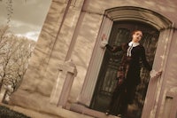 a woman is standing on the steps of a pink building